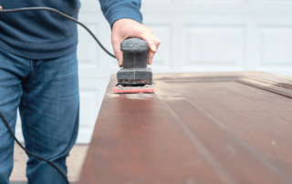 A person using an electric sander on a wooden surface.
